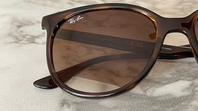 May include: Brown Ray-Ban sunglasses with a tortoiseshell frame. The lenses are a gradient brown color. The Ray-Ban logo is visible on the upper left corner of the frame.