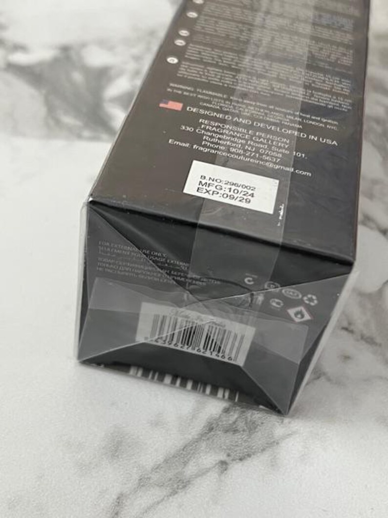 May include: A black rectangular box with text and a barcode. The box is labeled "DESIGNED AND DEVELOPED IN USA" and includes contact information for the manufacturer. The expiration date is printed on a white sticker.