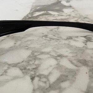 K&ouml;nnte beinhalten: Schwarze Sonnenbrille mit rechteckiger Linsenform. Der Rahmen ist schwarz und hat ein schlankes, modernes Design. Der B&uuml;gel hat ein kleines, geometrisches Detail am Ende.