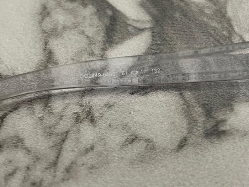 May include: Clear eyeglasses with the numbers "009449-0460 61 17 132" printed on the temple. The glasses are set against a textured, light-colored background.
