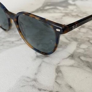 May include: Sunglasses with a tortoiseshell pattern frame and dark lenses. The sunglasses have a classic design with a subtle logo on the temple. The frame is a mix of brown and black.