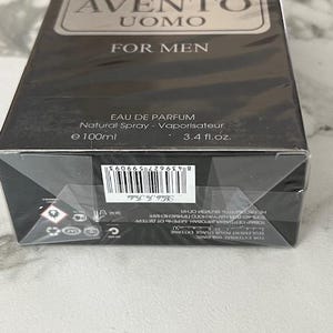 K&ouml;nnte beinhalten: Schwarzer rechteckiger Karton mit "AVENTO UOMO FOR MEN" Eau de Parfum. Die Schachtel hat silberne Schrift und ein silbernes rechteckiges Etikett. Die Schachtel enth&auml;lt 100 ml Parf&uuml;m.