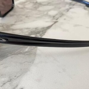 May include: Black sunglasses with a curved frame and dark lenses. The sunglasses have a glossy finish and a small logo on the temple. The design is sleek and modern, suitable for outdoor activities.