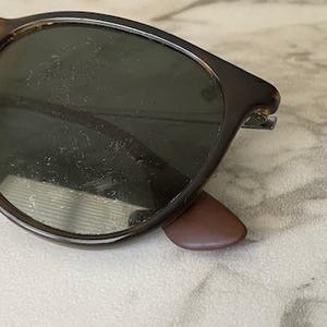 K&ouml;nnte beinhalten: Nahaufnahme einer Sonnenbrille mit Schildpattrahmen und dunklen Gl&auml;sern. Die Sonnenbrille hat eine klassische runde Form und braune B&uuml;gel. Die Gl&auml;ser scheinen zerkratzt zu sein. Die Sonnenbrille liegt auf einer hellen Oberfl&auml;che.