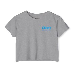 May include: A gray crop top with a crew neck. The shirt has short sleeves and features the text "CDOT" in blue, along with a star and the words "COLORADO DEPARTMENT OF TRANSPORTATION".