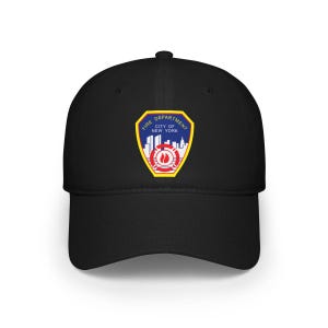 Op de afbeelding: Zwarte baseballcap met het embleem van de brandweer van New York City. Het embleem heeft de vorm van een schild met een blauwe rand, een stadsgezicht en de woorden "Fire Department City of New York".