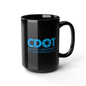 May include: A black ceramic mug with a large handle. The mug features the text "CDOT CHICAGO DEPARTMENT OF TRANSPORTATION" in blue. The mug is a standard size for coffee or tea.