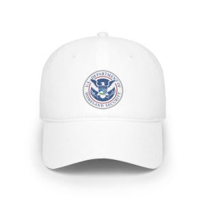 May include: A white baseball cap featuring the U.S. Department of Homeland Security emblem on the front. The emblem is circular, with a blue and white eagle, and the text "U.S. DEPARTMENT OF HOMELAND SECURITY" in a circular pattern.