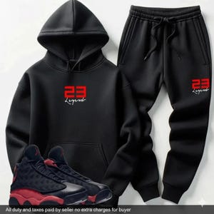 May include: Black hoodie and sweatpants set with red "23 Legend" text. Includes black and red sneakers. The hoodie has a drawstring hood and a front pocket. The sweatpants have a drawstring waist. A complete athletic outfit.