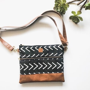 Sac à bandoulière flèche noir et blanc en toile de boue avec fermeture à glissière sur le devant et similicuir marron