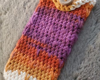May include: A handmade crochet phone case in a gradient of orange, purple, and yellow. The case has a flap with a wooden button closure and a white crocheted border. The case is designed to protect a phone.
