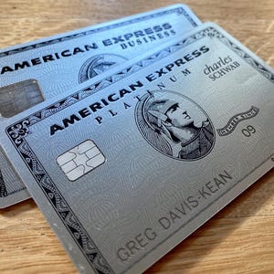 Pode incluir: Duas tarjetas de crédito American Express prateadas. Uma tarjeta está rotulada como "American Express Business", e a outra como "American Express Platinum" com o nome "Greg Davis-Kean". Ambas as tarjetas têm um chip e o logotipo American Express.