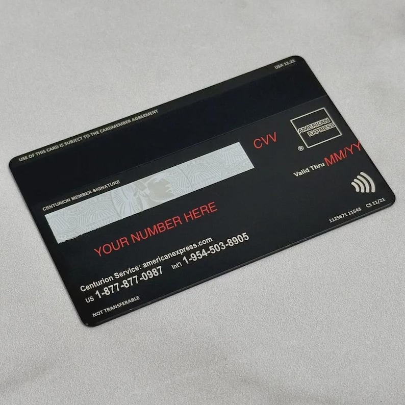 May include: Black American Express credit card with the text "YOUR NUMBER HERE" in red. The card also displays the American Express logo, a CVV code, and a "Valid Thru MM/YY" date. The card has a contactless payment symbol and the text "NOT TRANSFERABLE".