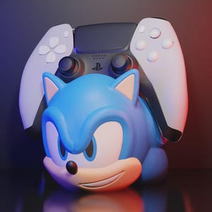 Può includere: Una figura blu di Sonic the Hedgehog con un controller PlayStation 5 bianco e nero dietro. La figura ha un'espressione sorridente ed è ambientata su uno sfondo scuro con illuminazione rossa e blu.