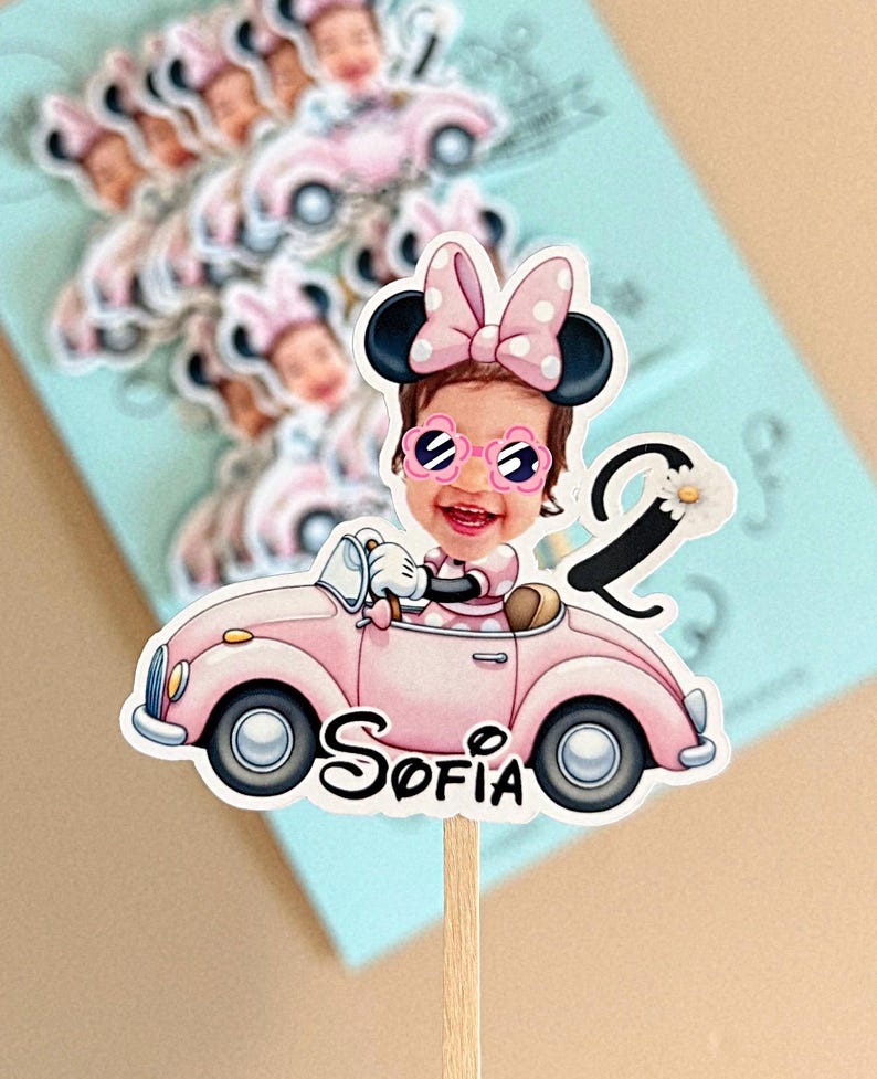 May include: A custom cake topper featuring a cartoon-style illustration of a child with a photo-realistic face, wearing Minnie Mouse ears and flower-shaped sunglasses, driving a pink convertible car with the name Sofia and the number 2.