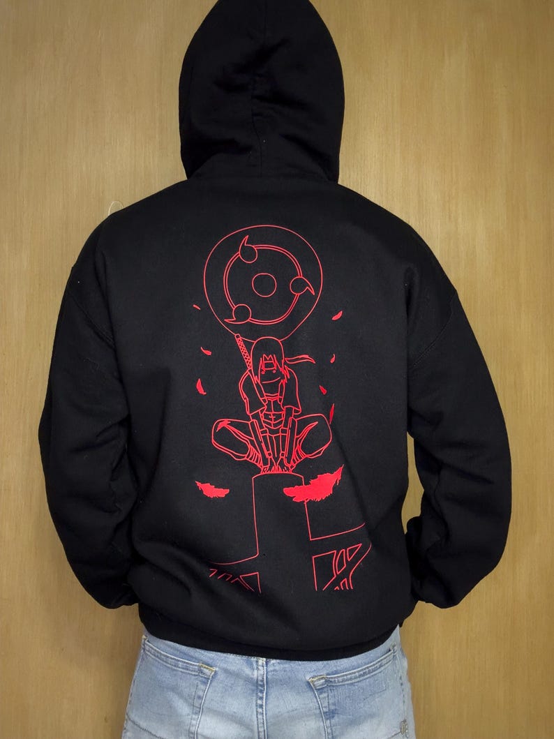 May include: Black hooded sweatshirt with a red graphic on the back. The graphic features a character with a sword and a circular design with three tomoe. The sweatshirt has a drawstring hood and long sleeves.