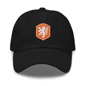 May include: Black baseball cap with a curved brim. The cap features an embroidered orange and white crest with a lion design. The crest is in a shield shape and is centered on the front of the cap.