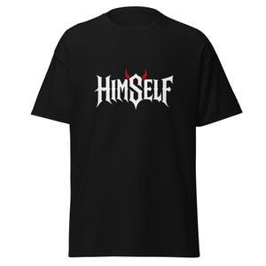 Könnte beinhalten: Schwarzes T-Shirt mit dem Wort "HIMSELF" in gotischer Schrift, mit roten Teufelshörnern über dem Text. Das Shirt ist ein kurzärmeliger, lässiger Stil.