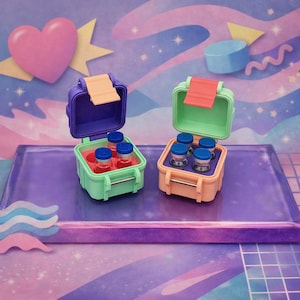 May include: Two small, square, hinged storage cases with latch closures. The left case is purple and mint green with a peach latch, containing four small glass vials with blue caps. The right case is mint green and peach with a coral latch, also holding four small glass vials with blue caps.