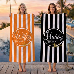 May include: Two rectangular beach towels with vertical stripes. One towel is orange and white with a circular graphic reading Wifey EST. 2026 Sloane. The other is black and white with a circular graphic reading Hubby EST. 2026 Miles.