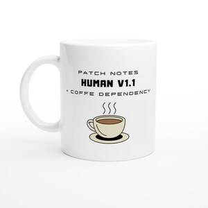 Puede incluir: Taza de café de cerámica blanca con asa curvada. La taza presenta el texto "PATCH NOTES HUMAN V1.1 + COFFEE DEPENDENCY" y un gráfico de una taza de café humeante. Un diseño humorístico para los amantes del café.