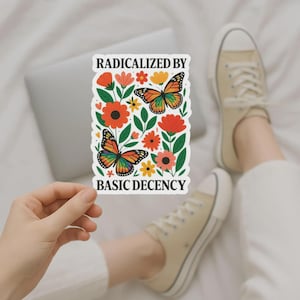 May include: A rectangular sticker with a floral design and two butterflies with rainbow wings. The sticker includes the text "RADICALIZED BY BASIC DECENCY". The flowers are orange and yellow, with green leaves.