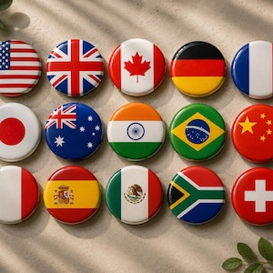 Könnte beinhalten: Eine Sammlung von fünfzehn runden Ansteckbuttons, die jeweils eine andere Nationalflagge zeigen. Die Flaggen umfassen die der Vereinigten Staaten, des Vereinigten Königreichs, Kanadas, Deutschlands, Frankreichs, Japans, Australiens, Indiens, Brasiliens, Chinas, Italiens, Spaniens, Mexikos, Südafrikas und der Schweiz.