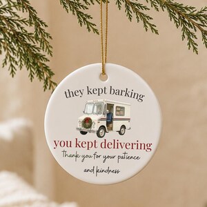 Può includere: Un ornamento rotondo in ceramica bianca appeso a un cordino dorato. Presenta la grafica di un furgone per le consegne bianco con una ghirlanda natalizia sul davanti. Il testo recita: they kept barking, you kept delivering, Thank you for your patience and kindness.