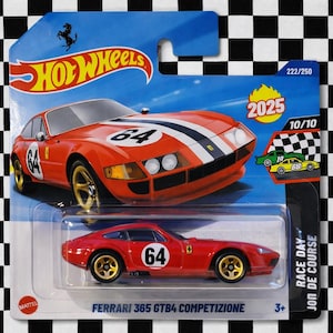 以下が含まれることがあります： 金色のホイールと番号64が付いた、赤いHot Wheels Ferrari 365 GTB4 Competizioneのダイキャストカー。パッケージには、Hot Wheelsのロゴ、2025年、および「RACE DAY JON DE COURSE」というテキストが含まれています。