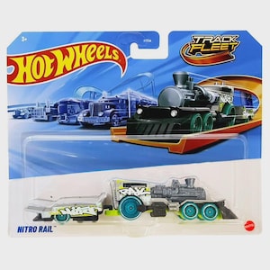 Może przedstawiać: Zabawkowa kolejka Hot Wheels Nitro Rail na niebiesko-białym tle. Zabawkowa kolejka jest szara i czarna z zielonymi kołami i tekstem w stylu graffiti. Opakowanie zawiera logo Hot Wheels i napis "Track Fleet."