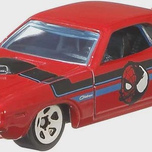 May include: A red Dodge Challenger toy car with black and blue stripes, a Spider-Man graphic, and the Marvel logo. The hood features a black air intake and a spider emblem. The car has white-rimmed wheels.