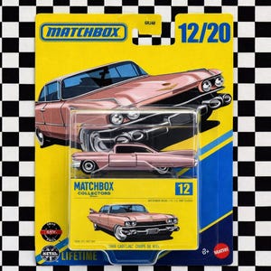 Könnte beinhalten: Ein Matchbox Collectors Spielzeugauto, ein Modell eines 1966 Cadillac Coupe de Ville, in Rosa, auf einer gelb-blauen Karte. Auf der Karte steht "MATCHBOX" und "12/20". Das Spielzeugauto befindet sich in einer transparenten Kunststoffbox.
