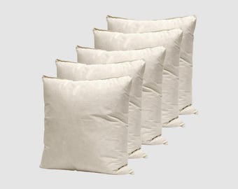 May include: Five off-white square pillows arranged diagonally. The pillows have a soft, textured appearance and are filled, suggesting comfort. The neutral color and simple design make them suitable for various decor styles.