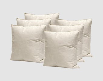 May include: Six square, off-white pillows are arranged in a group. The pillows have a soft, slightly wrinkled appearance and a neutral color. The edges of the pillows have a subtle, darker trim. The pillows are likely for home decor or bedding.