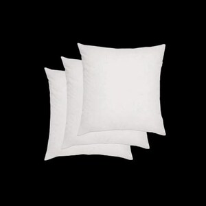May include: Three square, white pillows are stacked against a black backdrop. The pillows have a soft, fluffy appearance, suggesting they are filled with down or a similar material. The pillows are arranged in a slightly overlapping manner.