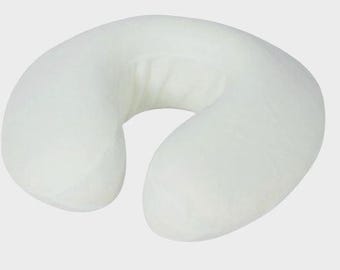 May include: A white, U-shaped massage pillow. The pillow is designed to support the neck and head, with a curved shape and a central opening. The pillow is made of a soft, plush material.