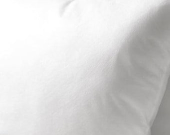 May include: Close-up of a white pillow with a soft, textured surface. The pillow is square-shaped and appears to be made of a smooth fabric. The lighting creates subtle shadows, highlighting the pillow's shape and texture.