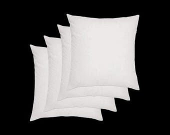May include: Four square, white pillow inserts are stacked against a black background. The pillows are fluffy and appear to be made of a soft material. The pillows are a neutral color and can be used for decorative purposes.