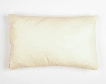 May include: A rectangular, cream-colored pillow on a white background. The pillow has a soft, slightly wrinkled appearance, suggesting a comfortable, plush filling. The pillow's dimensions are not visible.