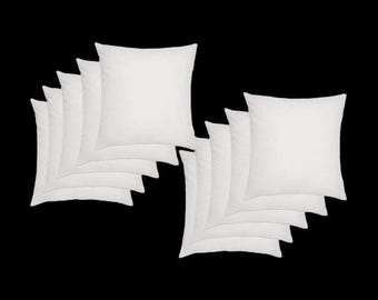 May include: A collection of white square pillows arranged in two groups against a black background. Each pillow appears to be filled and fluffy, with a clean, simple design. The pillows are likely for home decor or bedding.