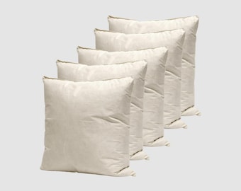May include: Five off-white square pillows arranged diagonally. The pillows have a soft, textured appearance and are filled, suggesting comfort. The neutral color and simple design make them suitable for various decor styles.