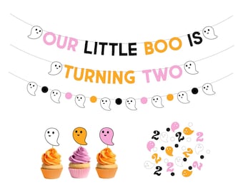 May include: A Halloween-themed party banner with the text "Our Little Boo Is Turning Two" in black, orange, and pink letters. The banner is decorated with white ghost cutouts.