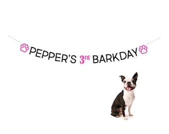 May include: A black and white Boston Terrier dog sits in front of a banner that reads "PEPPER'S 3rd BARKDAY" with pink paw prints on either end.