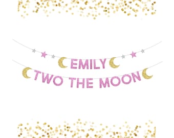 May include: A pink glitter banner with the text "EMILY TWO THE MOON" and gold glitter crescent moons and stars. The banner is strung on a thin silver string, ideal for a birthday celebration.