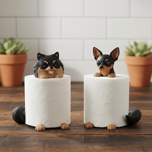 Può includere: Due portarotoli di carta igienica originali con figurine di cani. Uno è un Pomerania nero e marrone, l'altro un Chihuahua nero e marrone. Entrambi i cani sembrano emergere da rotoli di carta igienica bianchi, con le zampe e le code visibili.