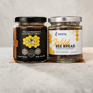 May include: Two glass jars of natural health products. One jar is labeled "Health Harvest Rainforest Honey" with a bee graphic. The other jar is labeled "Rosita Wild Bee Bread" and is a dietary supplement. The honey jar weighs 10 oz.