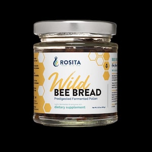 Könnte beinhalten: Ein Glas mit silbernem Deckel, beschriftet mit "Wild Bee Bread". Das Etikett zeigt das "Rosita"-Logo und den Text, der darauf hinweist, dass es sich bei dem Produkt um vorverdauten fermentierten Pollen, ein Nahrungsergänzungsmittel, handelt. Das Glas enthält eine dunkle, körnige Substanz.