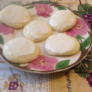 Peut inclure: Une assiette de biscuits au citron avec un gla&ccedil;age blanc et un motif floral. Les biscuits sont sur une assiette blanche avec un bord brun et un motif floral.