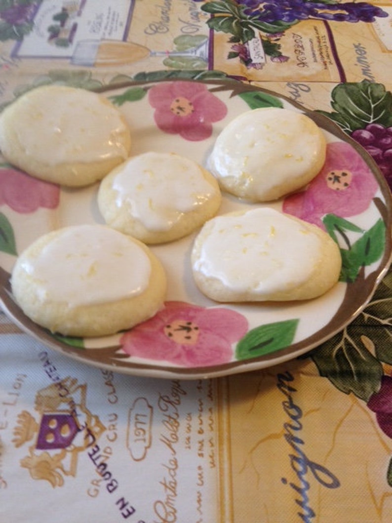 Peut inclure: Une assiette de biscuits au citron avec un gla&ccedil;age blanc et un motif floral. Les biscuits sont sur une assiette blanche avec un bord brun et un motif floral.