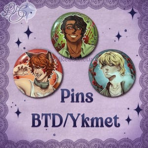 May include: Three round pins with anime-style character illustrations. One pin features a character with red hair and fox ears, another with a smiling character, and the third with a character surrounded by red flowers. The word "Pins" and "BTD/Ykmet" are printed on the image.
